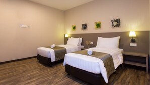 Habitación de hotel con dos camas, suelo de madera y lámparas fijadas a la pared.