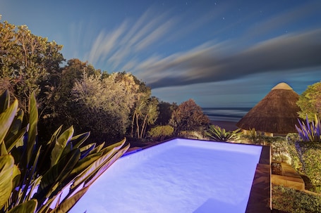 Una piscina al aire libre, sombrillas, sillones reclinables de piscina