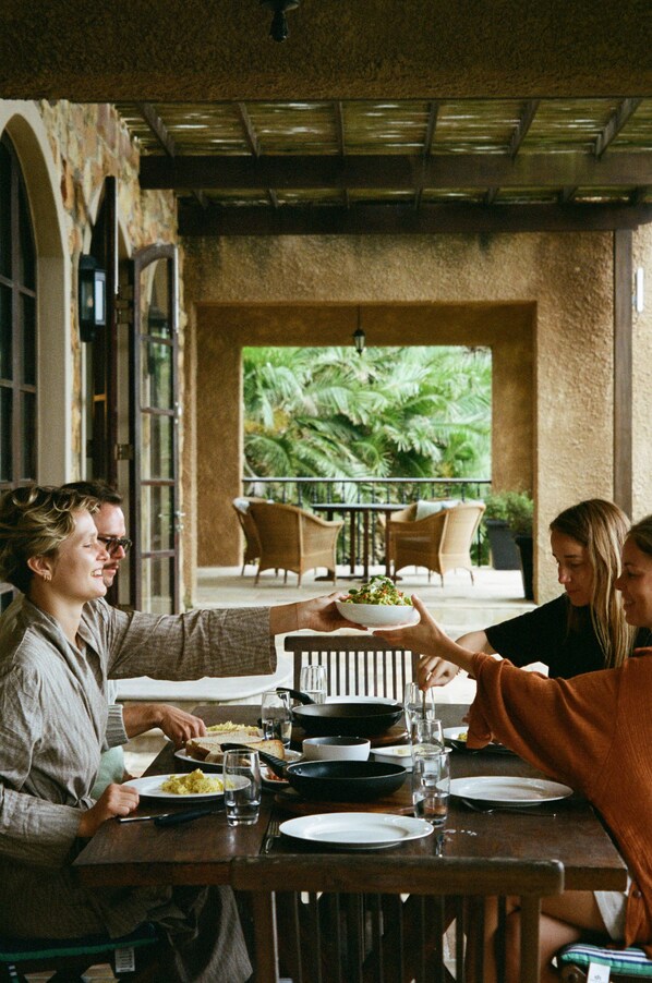 A dining area with a table set for four, surrounded by stone walls and a view of greenery. - Buccara Noetzie - Pezula Castle (Knysna)