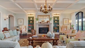 A spacious living room with a fireplace, comfortable seating, and a chandelier. - Buccara Noetzie - Pezula Castle (Knysna)