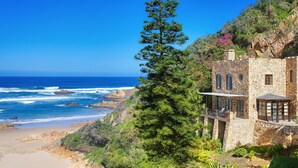 A coastal stone building with a balcony overlooking the beach and ocean. - Buccara Noetzie - Pezula Castle (Knysna)