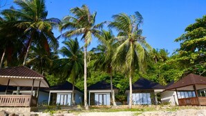 En ejendom ved stranden med flere huse i bungalowstil, hver med balkon og havudsigt.