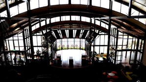 A spacious interior with a central dining area, large windows, and a curved ceiling structure.