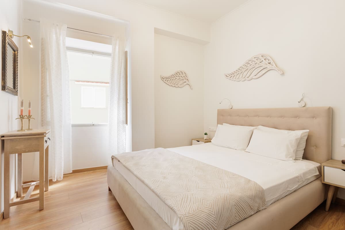 Une chambre à coucher avec un grand lit, une table de chevet, une commode et des œuvres d’art décoratives au mur.