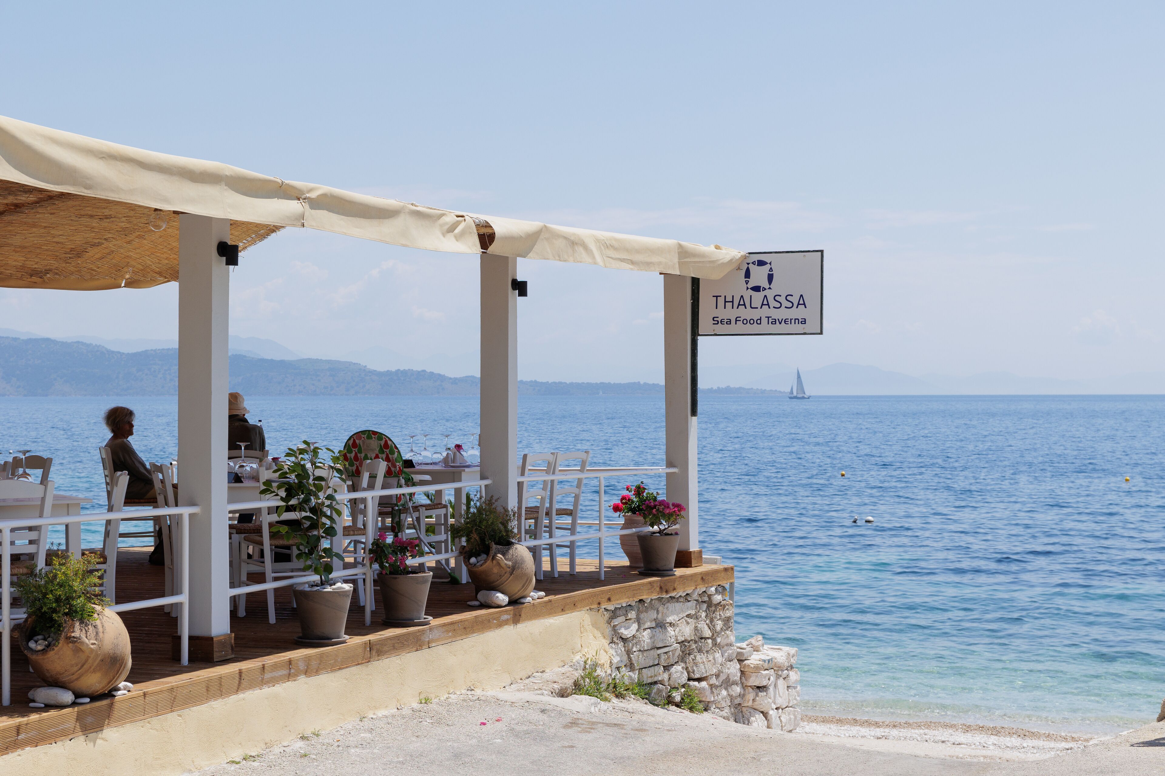 A seaside restaurant named Thalassa with outdoor seating and potted plants.