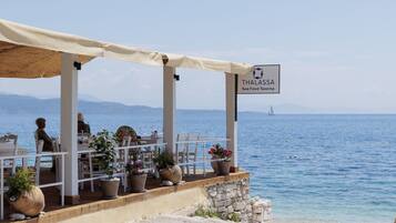 A seaside restaurant named Thalassa with outdoor seating and potted plants.