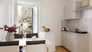 A modern kitchen with white cabinets, a white countertop, and a dining area with a table and chairs. - Salt and Sun Apartments by Konnect, Kaminaki Beach (Corfu)