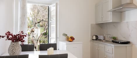 Une cuisine moderne avec des meubles blancs, un plan de travail blanc et un coin repas comprenant une table et des chaises.