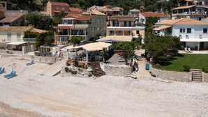 A coastal area with buildings, a beach, and a small structure with outdoor seating. - Salt and Sun Apartments by Konnect, Kaminaki Beach (Corfu)