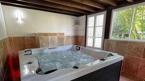 Ein Whirlpool in einem Raum mit gefliesten Wänden und einer Holzbalkendecke.
