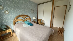 A bedroom with a bed, a nightstand, a chair, and a wardrobe.