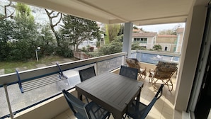 A balcony with a table and chairs, a view of the neighborhood, and a railing.