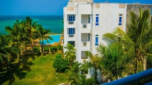 A multi-story building with balconies overlooking a pool and the sea. - Stay.Plus Almasi Beachfront Apartments (Mombasa)