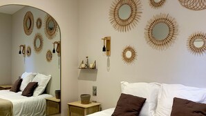 A hotel room with a large bed, a bedside table, a mirror, and wall-mounted decorative mirrors.