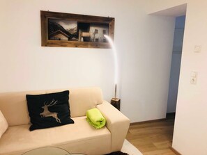 Ein Wohnzimmer mit einem beigefarbenen Sofa, einem gerahmten Bild an der Wand und einer Stehlampe.
