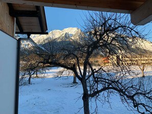 A snow-covered landscape with mountains in the background and a tree in the foreground.