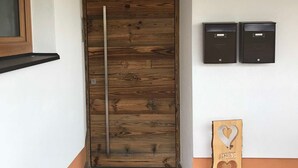 Puinen ovi, jossa on metallinen kahva, postilaatikko ja puinen kyltti, jossa on sydän- ja jäniskuva.