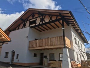 A two-story building with a balcony, wooden beams, and a white facade.