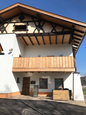 A two-story building with a balcony, a wooden facade, and a clear sky.