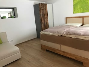 A bedroom with a bed, a nightstand, a dresser, and a window. - Jonagold Apartment - Schusterbrand Apartments (Absam)