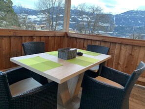 Une terrasse en bois avec une table et des chaises, offrant une vue sur un paysage montagneux.