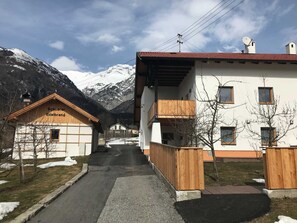 A mountain village with a building labeled 'Schuster Edelbrand' and a snow-covered mountain in the background. - Gravensteiner - Schusterbrand Apartments (Absam)