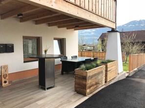 Une terrasse extérieure avec une table à manger, des chaises, une plateforme en bois et une vue sur une montagne.