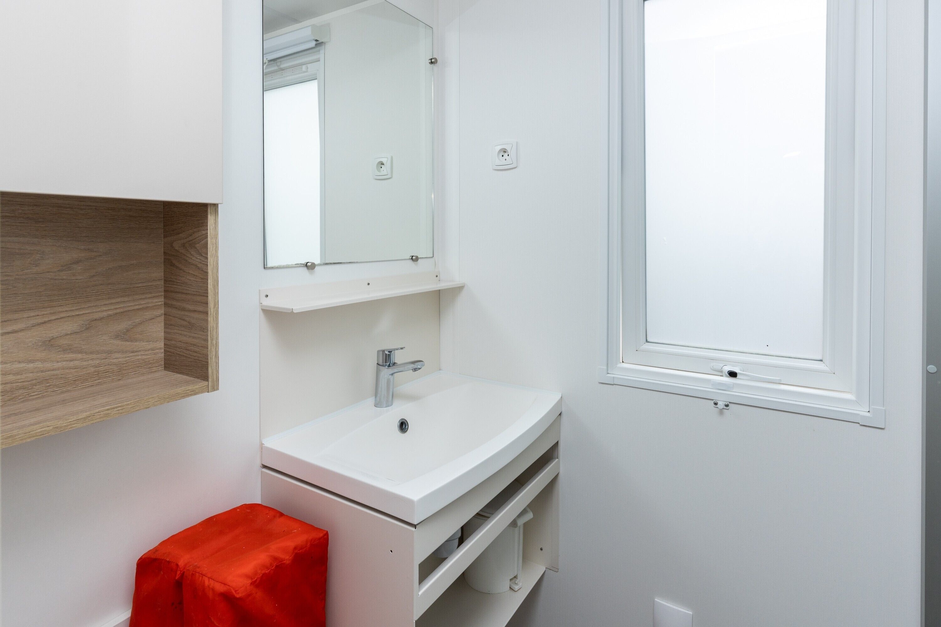 Une salle de bain moderne avec un lavabo blanc, un miroir et une fenêtre.