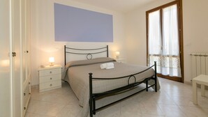 Une chambre à coucher avec un lit, des tables de chevet, une fenêtre avec des rideaux et une porte.