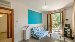 Une pièce comprenant un canapé, une table à manger, un téléviseur et donnant sur l’extérieur.