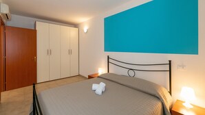 Une chambre à coucher comprenant un lit, une armoire, une table de chevet et un climatiseur fixé au mur.