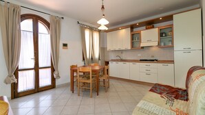 A kitchen with a dining table and chairs, a sofa, and cabinets. - Apartment 'Bilocale Ciliegiolo' with Terrace, Shared Pool & Wi-Fi (Suvereto)