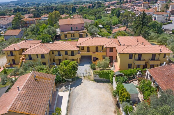 A residential area with multiple two-story houses, each with a tiled roof and surrounded by greenery.