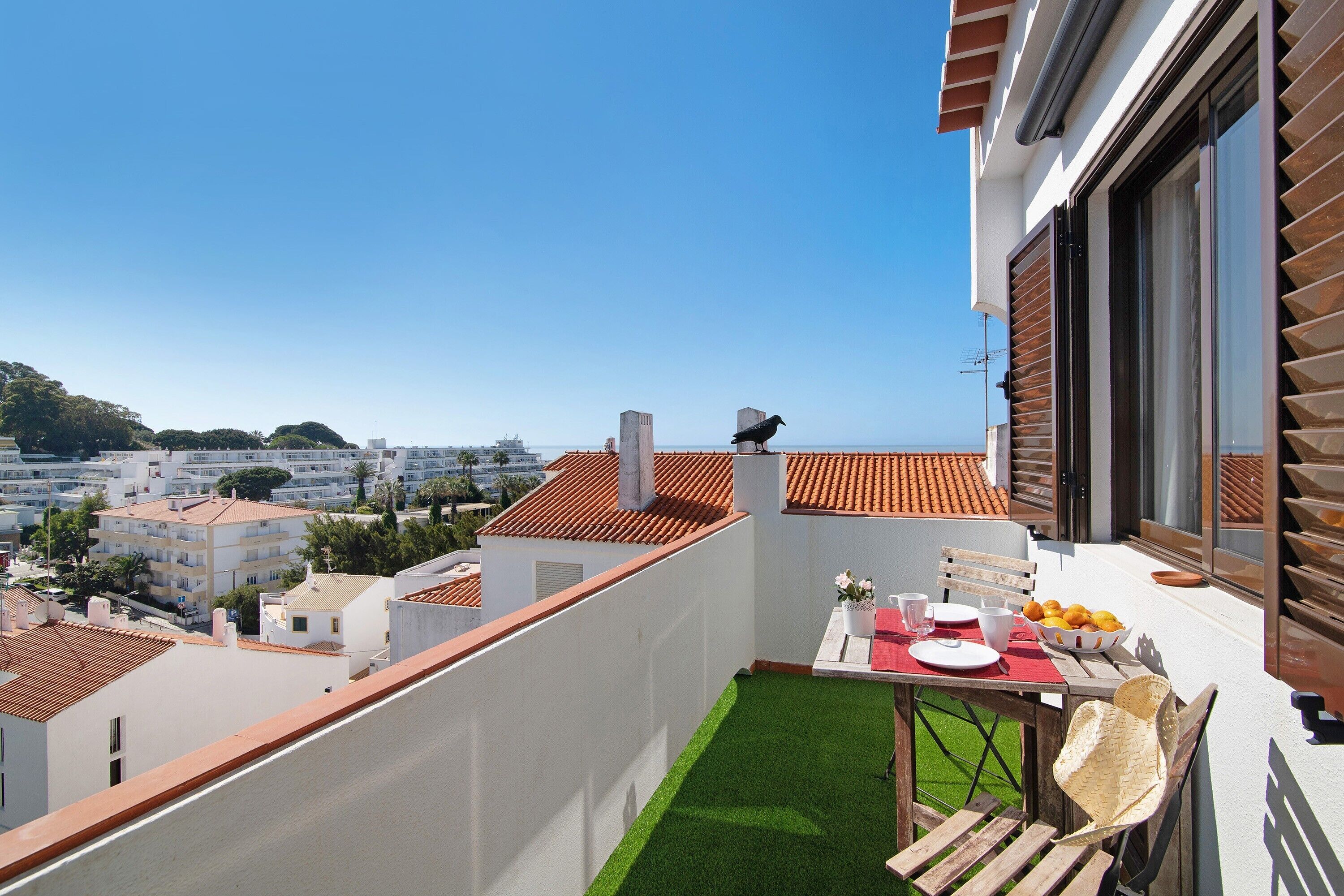 A balcony with a table set for dining, a chair, and a view of the cityscape.