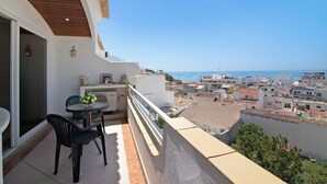 A balcony with a table and chairs, overlooking a coastal cityscape. - Apartment Paradis Bleu with Sea View, Shared Pool, Wi-Fi & A/C (Albufeira)