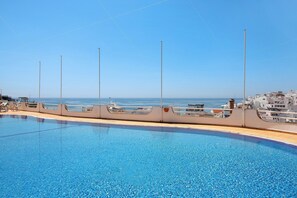 A swimming pool with a view of the sea and buildings in the background.