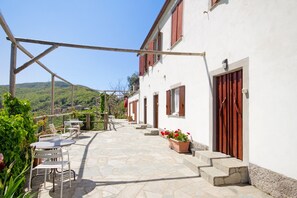 A building with a stone patio, outdoor seating, and a view of the hills.