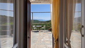 An open door leading to a patio with stone flooring, a table, and two chairs. - Apartment 'Fattorialmare Blu' with Sea View, Shared Garden and Wi-Fi (Camogli)