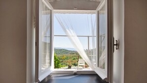 An open window with sheer curtains, a view of greenery and hills, and a small table with chairs outside. - Apartment 'Fattorialmare Blu' with Sea View, Shared Garden and Wi-Fi (Camogli)