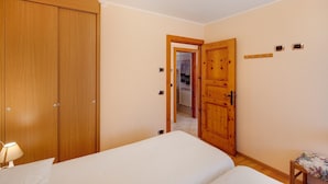 Una camera da letto con un'armadiatura in legno, un letto, un tavolino e una porta che dà su un corridoio.