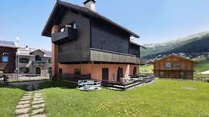 Un edificio a due piani con un balcone, un vialetto in pietra e un'area verde con mobili da giardino.