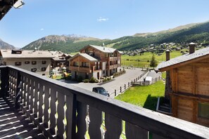 A wooden building with a balcony, a car parked in front, and a mountainous landscape in the background. - Apartment "Valleverde" with Mountain View, Balcony & Wi-Fi (Livigno)