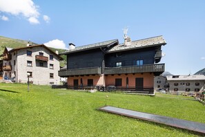 A two-story building with a balcony, a grassy area in front, and a clear sky.