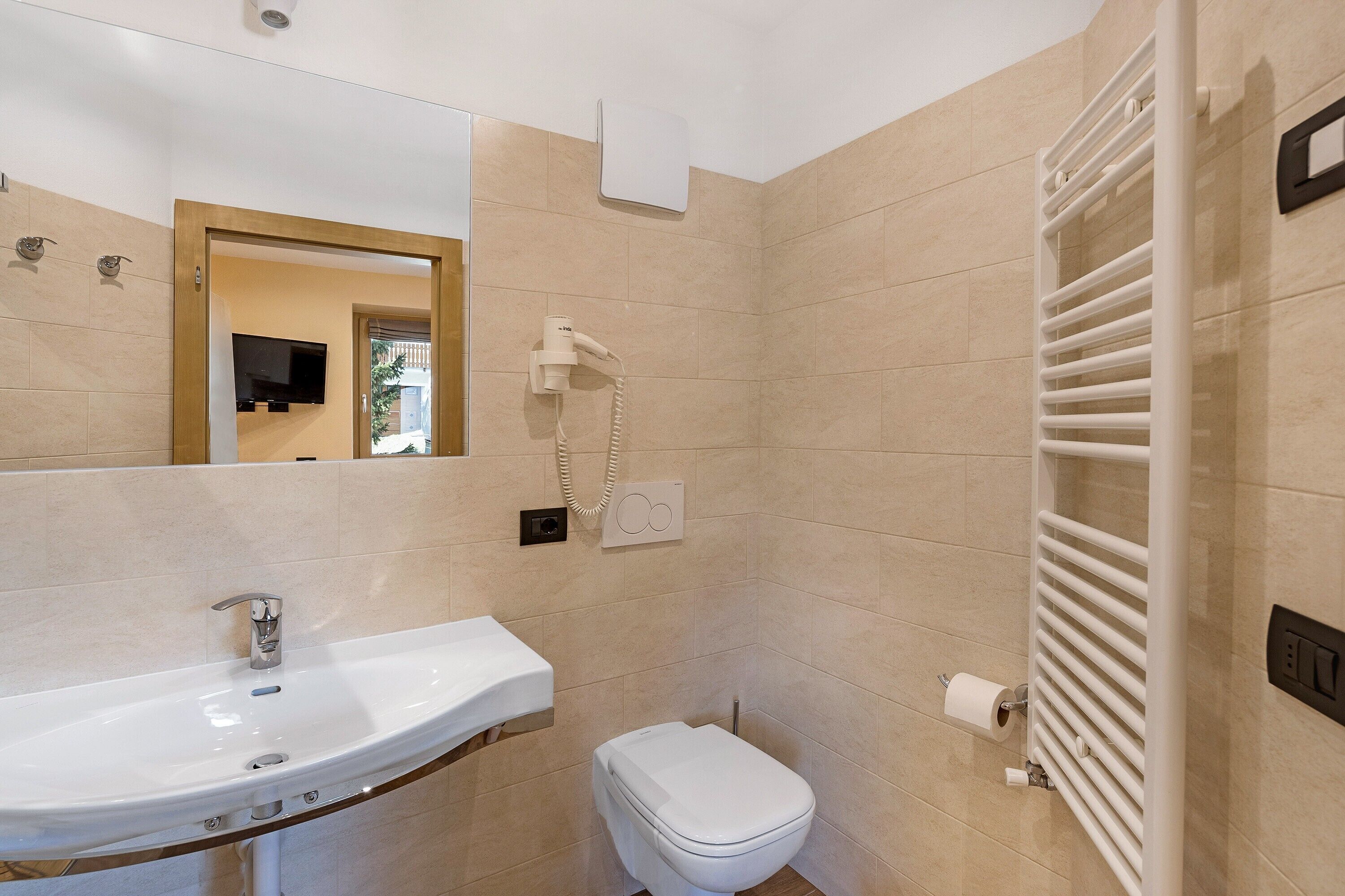 A bathroom with a sink, toilet, mirror, and towel rack.