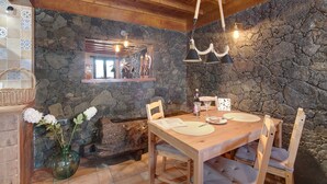 Un comedor rústico con pared de piedra, techo de madera y una mesa de madera con sillas.