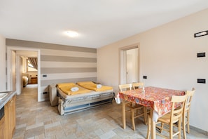 Une pièce de taille modeste comprenant un lit, une table à manger et un coin cuisine.