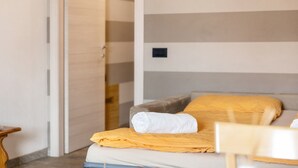 Ett hotellrum med en säng, ett litet bord i trä och en randig vägg.
