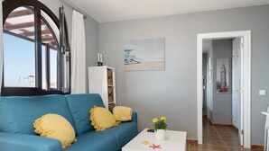 En stue med en blå sofa, et hvidt sofabord og et billede på væggen.