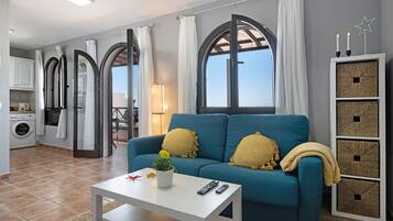 Un salón con sofá, una mesa de centro, una lámpara y vistas al cielo a través de amplios ventanales.