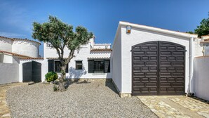 Un patio con un edificio blanco, un árbol y una gran puerta marrón.